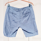 Blue shorts hanging on a wooden hanger against a white background
