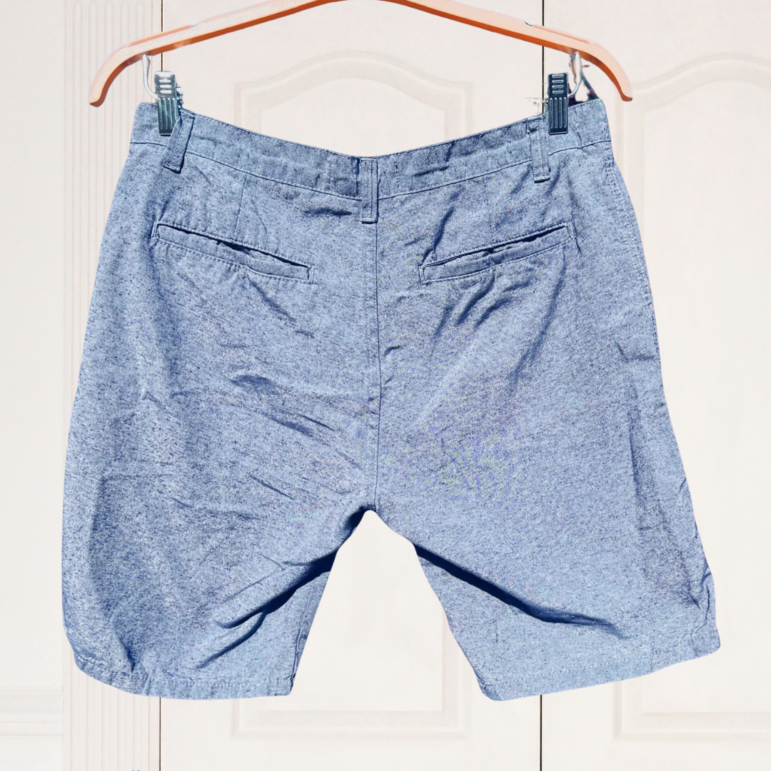 Blue shorts hanging on a wooden hanger against a white background