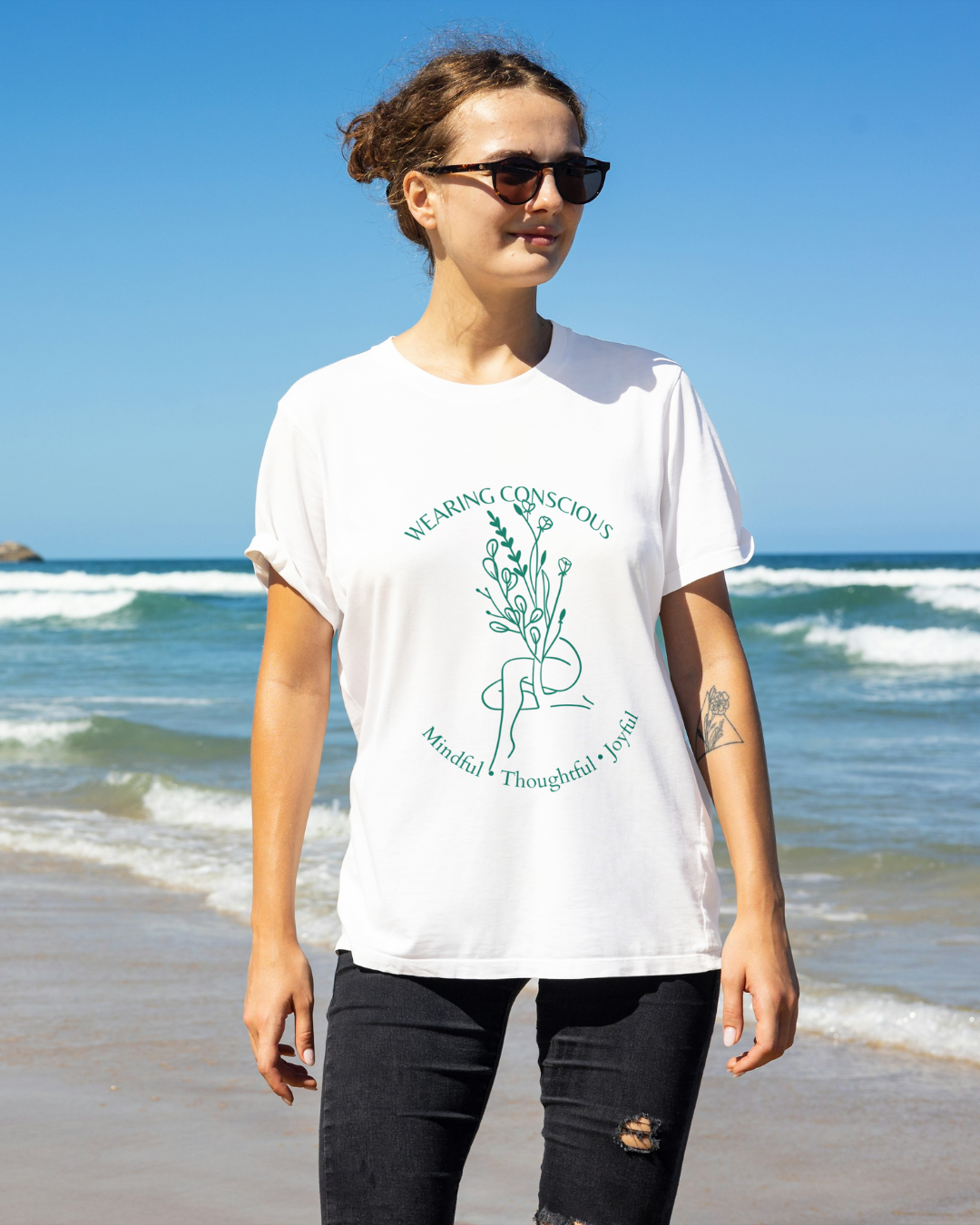Person wearing a white t-shirt with a graphic design on a beach