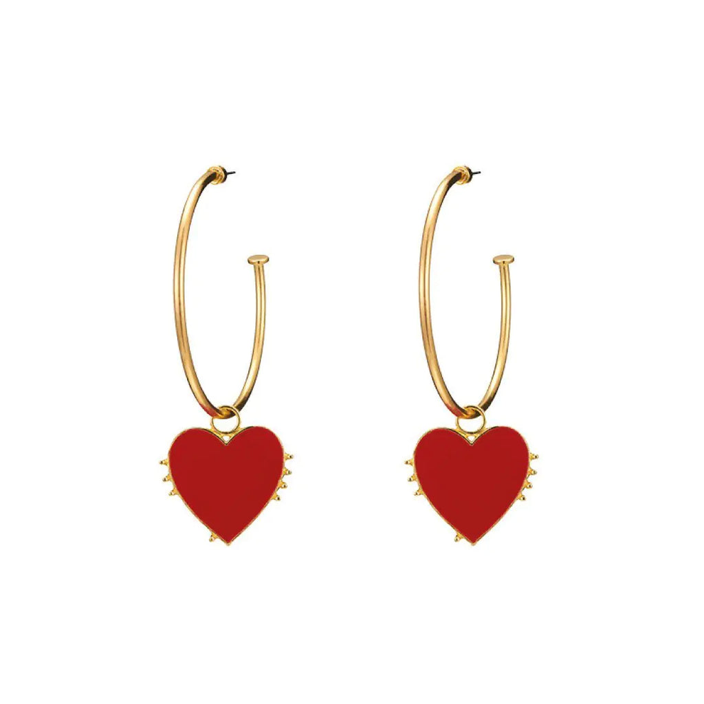 A pair of gold hoop earrings with a single red enamel heart design.