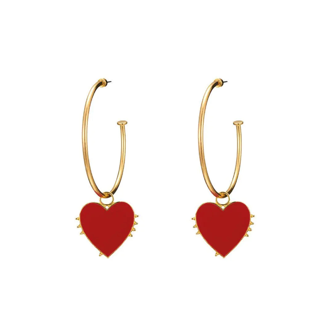A pair of gold hoop earrings with a single red enamel heart design.