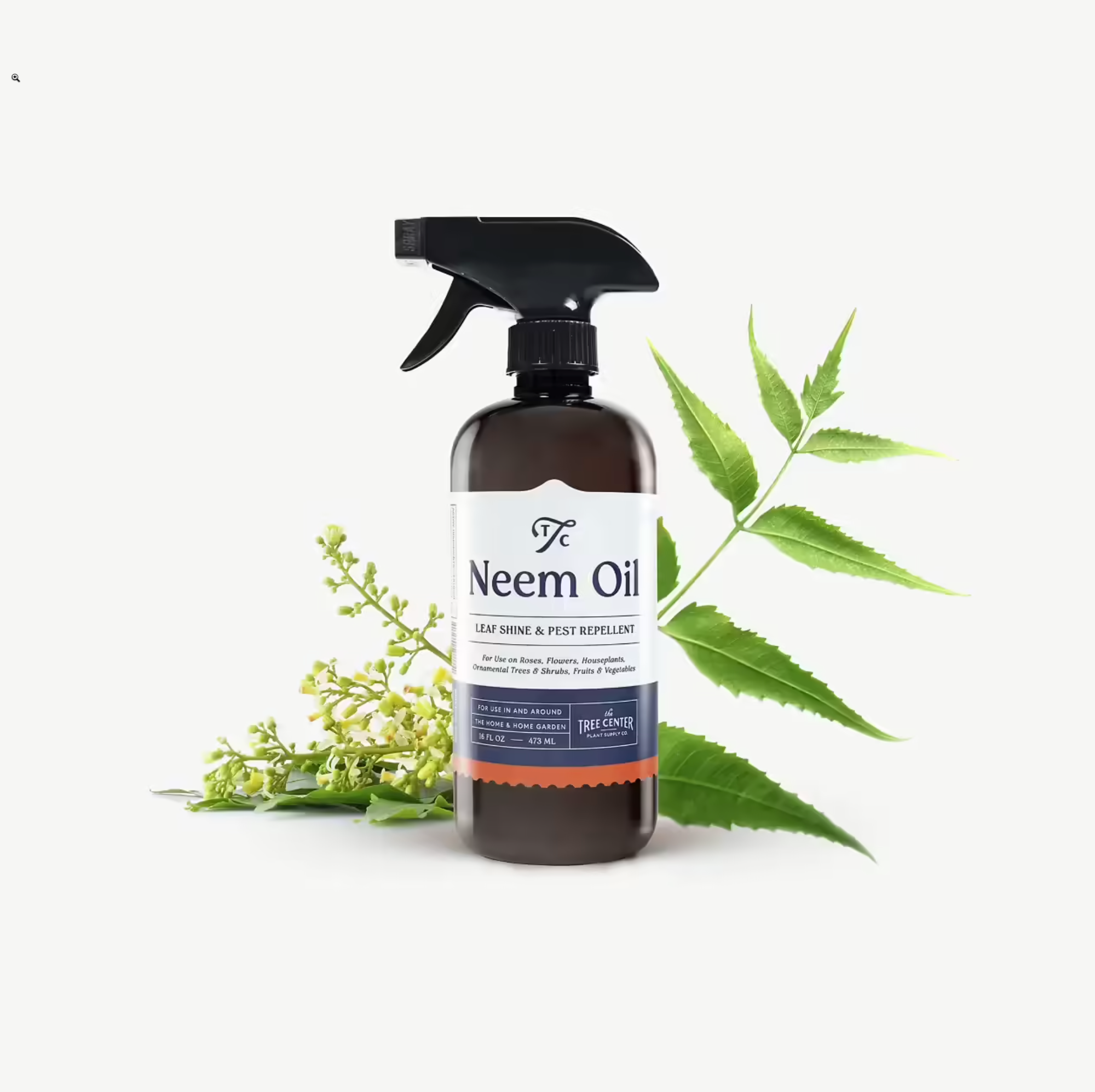 Bottle of neem oil with a spray nozzle on a white background with green leaves.