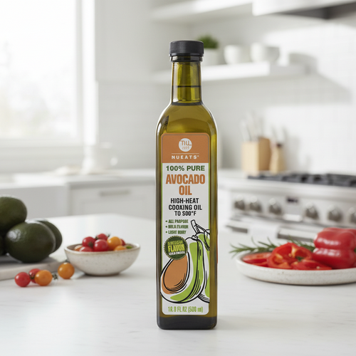 Bottle of avocado oil on a kitchen counter with avocados and tomatoes in the background