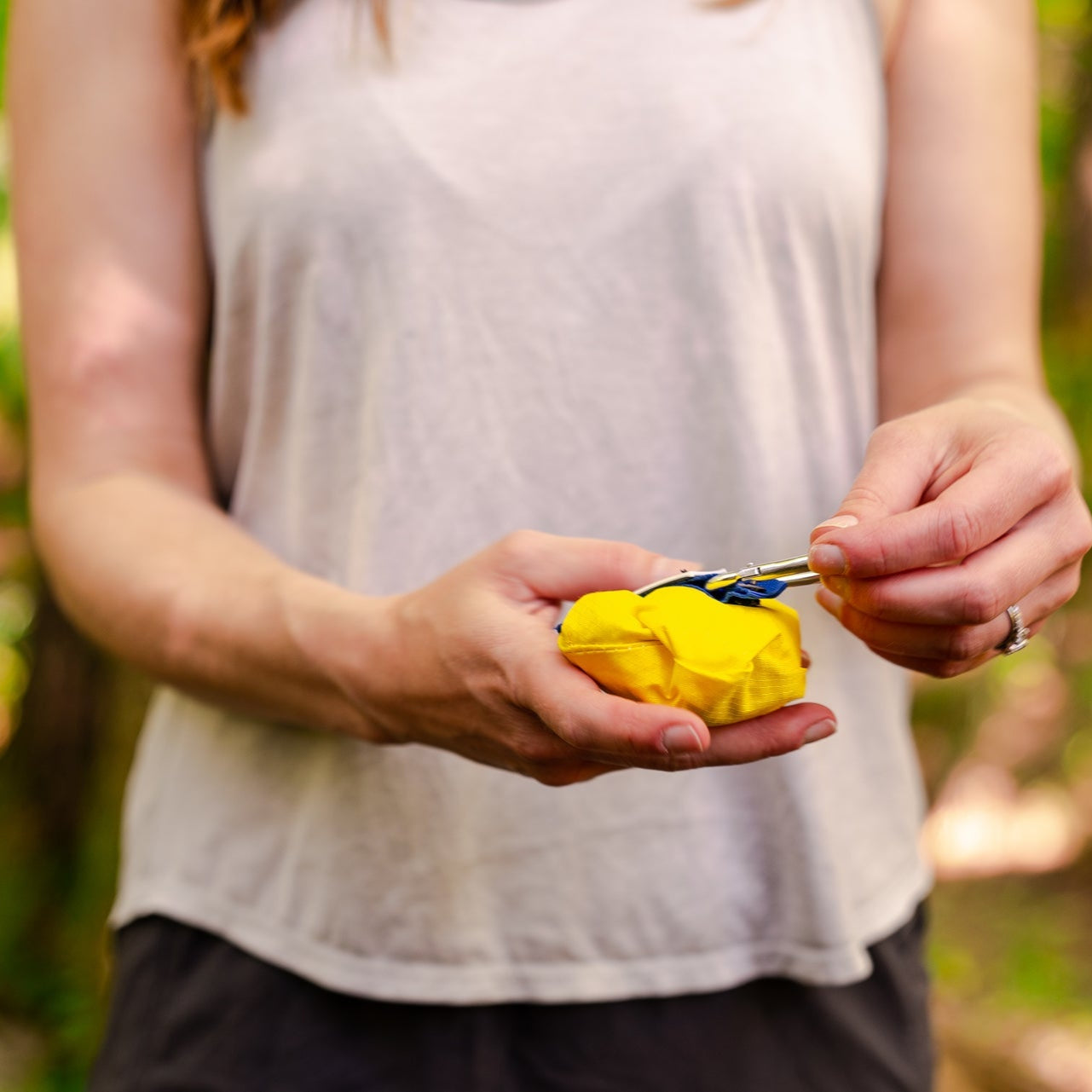 Person holding a yellow object outdoors with a blurred natural background