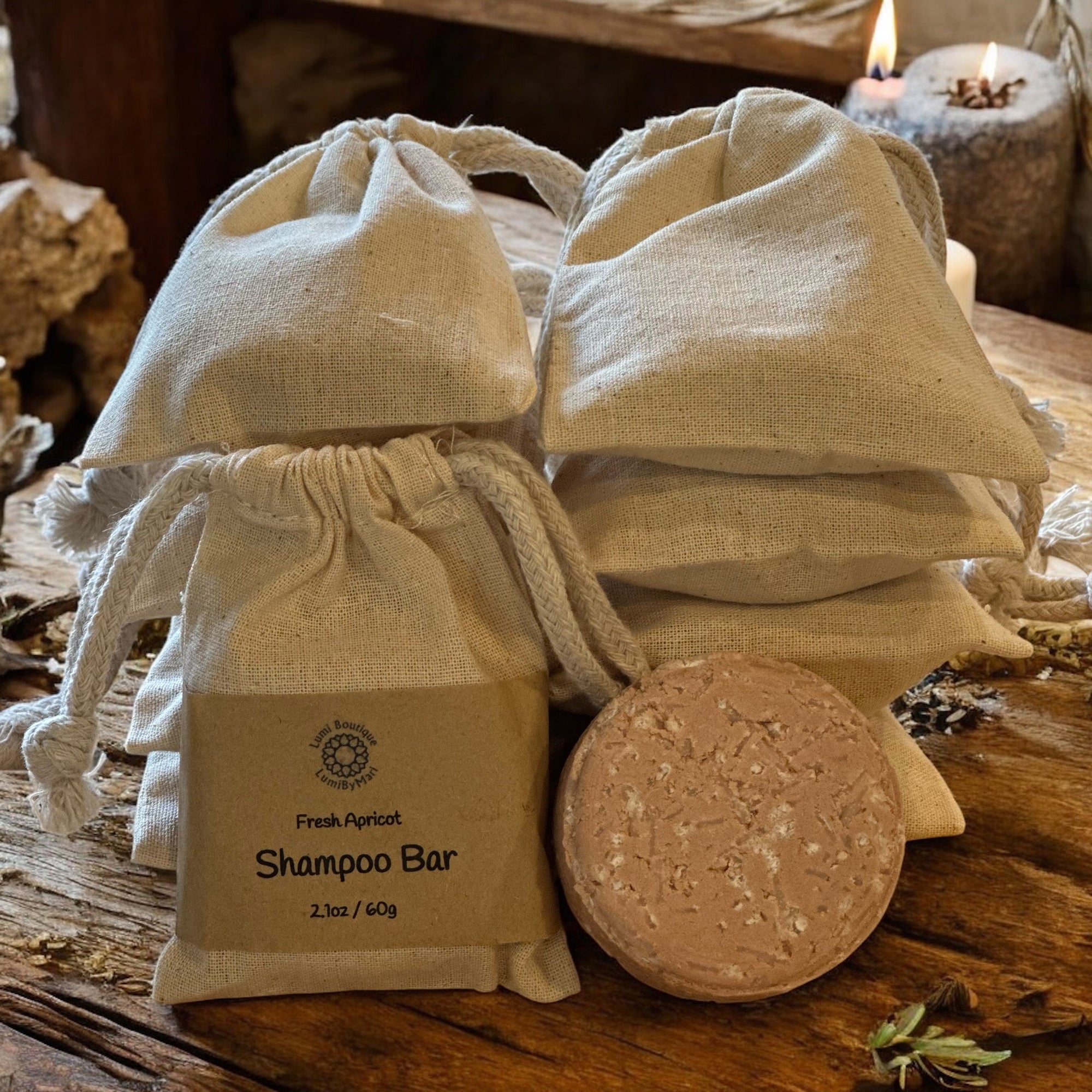 Shampoo bar in a drawstring bag with a round bar of soap on a wooden surface.