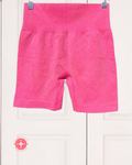 Pink shorts hanging on a white background
