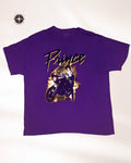 A purple short-sleeve t-shirt featuring a graphic print of the band Prince riding a motorcycle with the word 'Prince' written in a stylized font across the chest.
