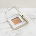 Single shimmery eyeshadow with a mirror on a marble surface