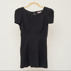 A black fitted mini dress with short sleeves, a high neckline, and a full back zip.