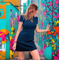 Woman in a black dress standing in front of colorful geometric wall art.