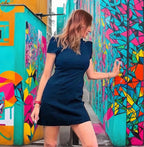 Woman in a black dress standing in front of colorful geometric wall art.