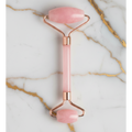 Two pink and rose gold facial rollers on a marble background