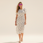 Woman wearing a white floral dress on a plain background