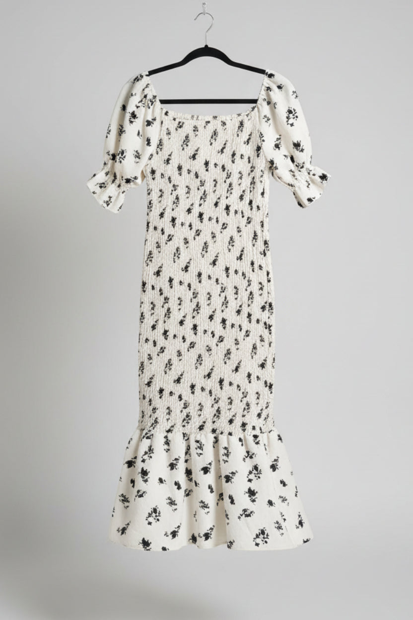 White floral dress with black patterns hanging on a bamboo fence
