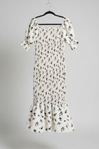 White floral dress with black patterns hanging on a bamboo fence