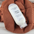 Body scrub bottle labeled 'Bourbon Vanilla' on a brown towel with a wooden background