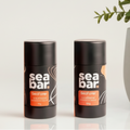 Two 'sea bar' products on a bathroom counter with a plant and mirror in the background.