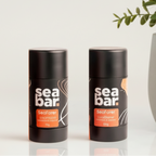 Two 'sea bar' products on a bathroom counter with a plant and mirror in the background.