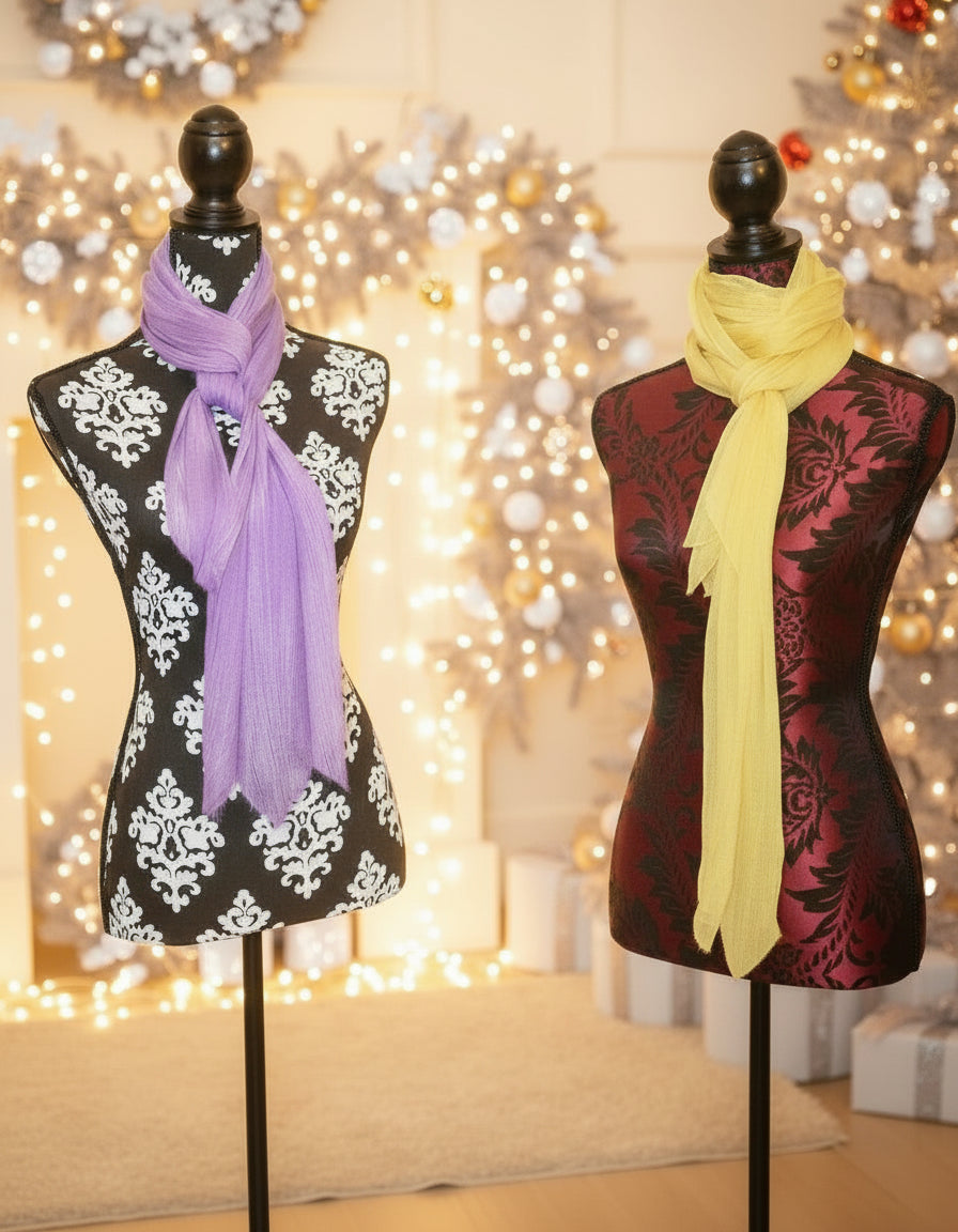 Two mannequins with scarves in a festive setting with Christmas trees and decorations.