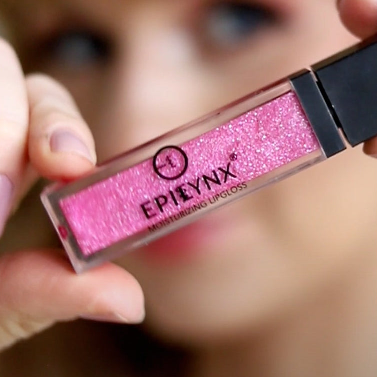 Pink lip gloss with Eplynx branding held by a hand against a blurred background