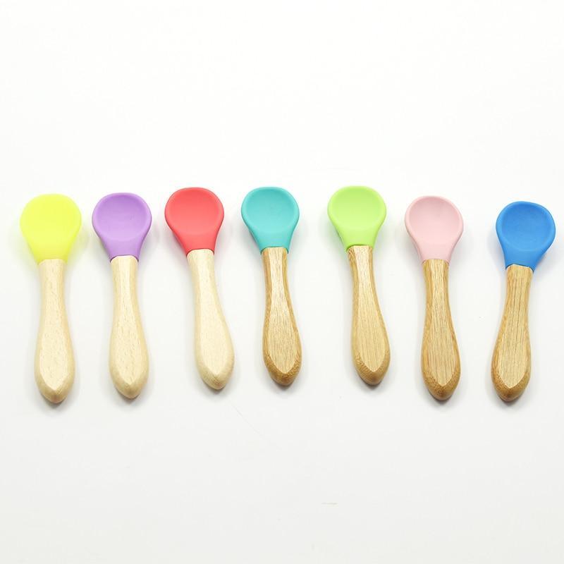 Set of colorful baby spoons with wooden handles on a white background