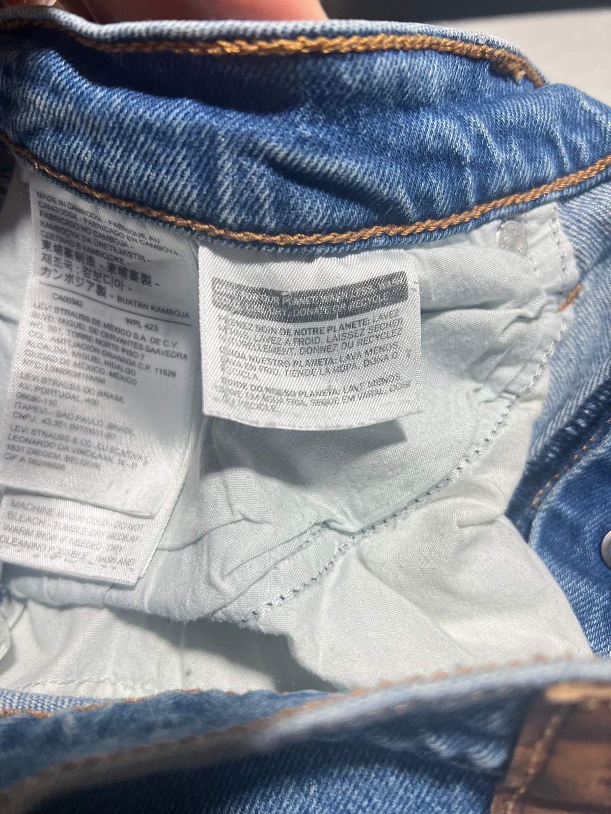 Close-up of the inside waistband of blue denim jeans, showing the white inner label with care instructions.