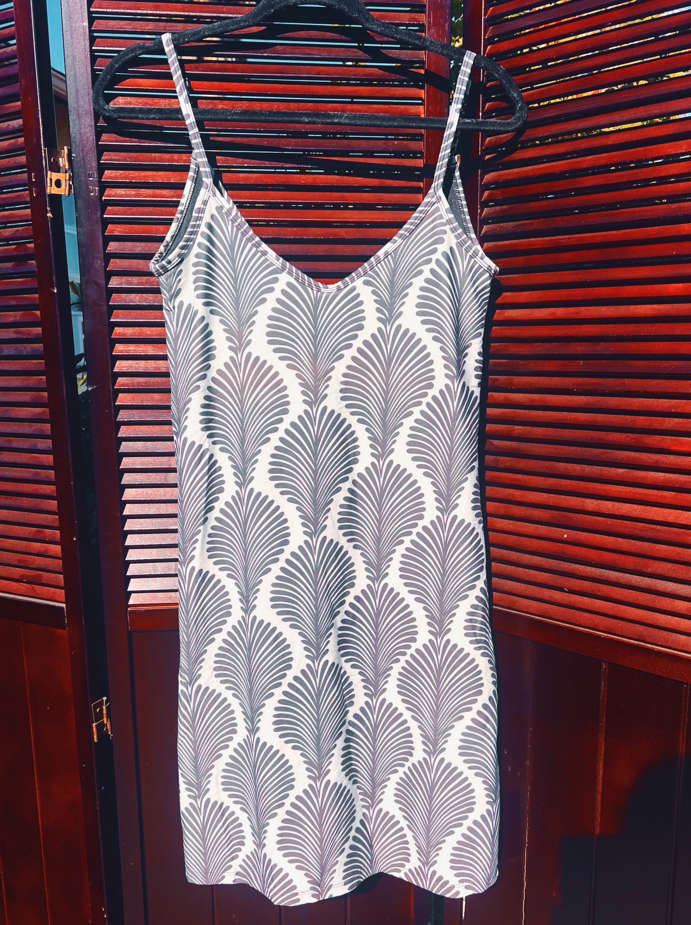 White patterned dress on a hanger against a red wooden background