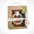 Sophie de Laval baby teething ring gift set in a brown kraft paper box with a clear window, tied with a cream ribbon. The set includes a white giraffe teething ring, a green and blue ring, a yellow and orange ring, and a white textured ring with pink, green, and orange accents.