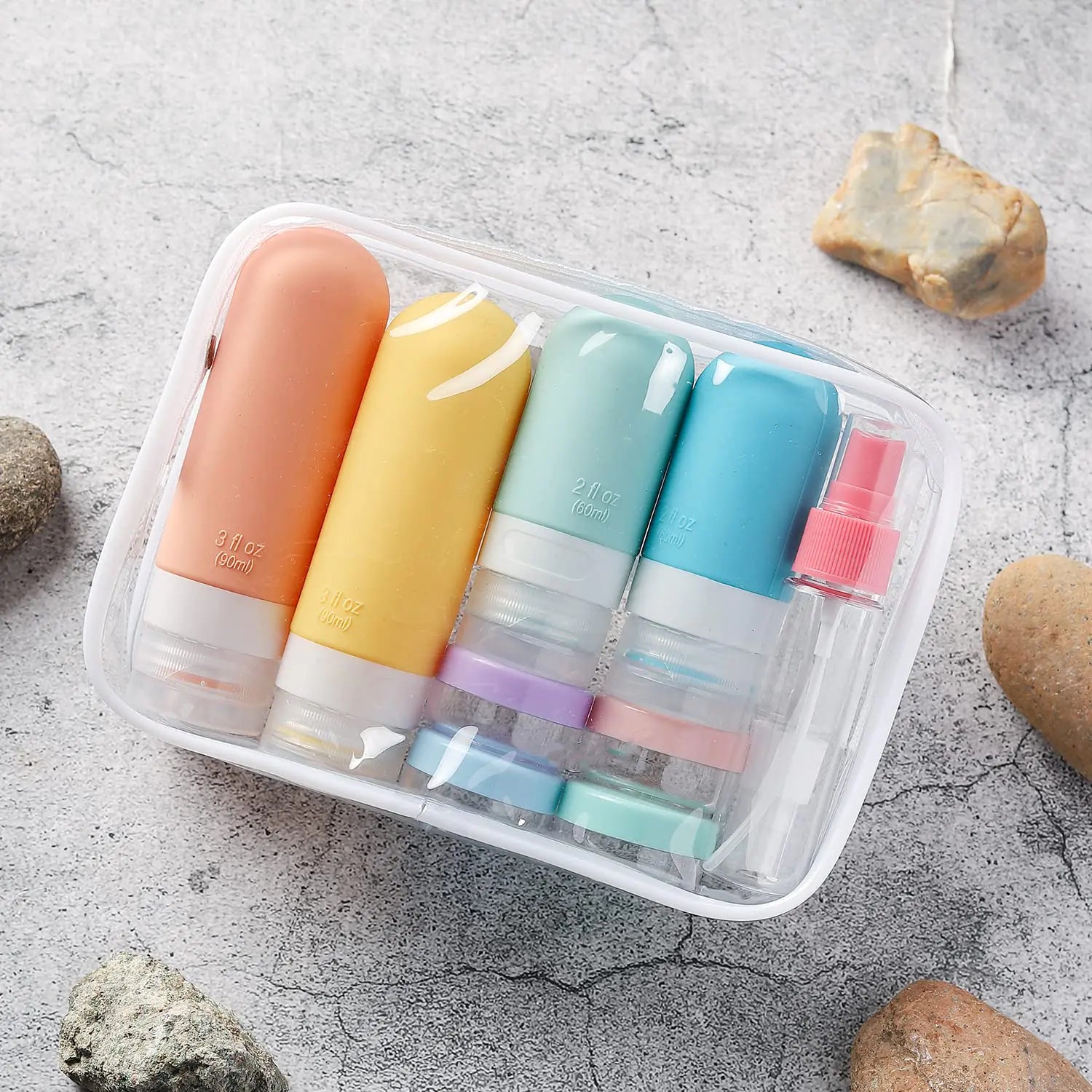 Set of colorful travel bottles with caps in a clear plastic case on a textured surface.