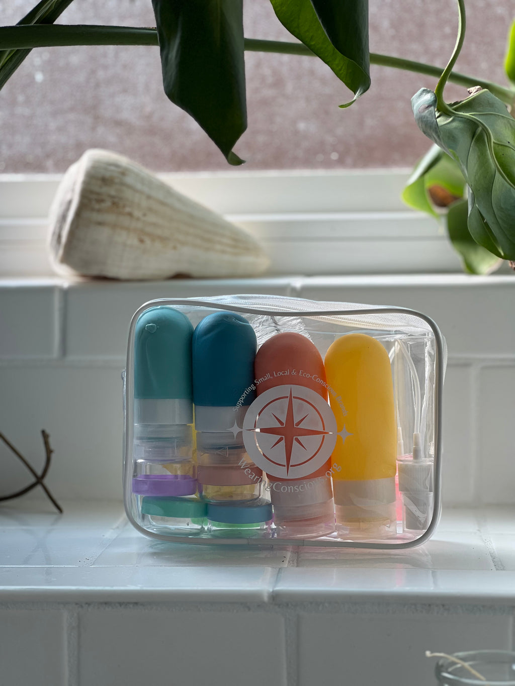 Set of colorful lip balm tubes in a clear container on a windowsill with plants in the background.