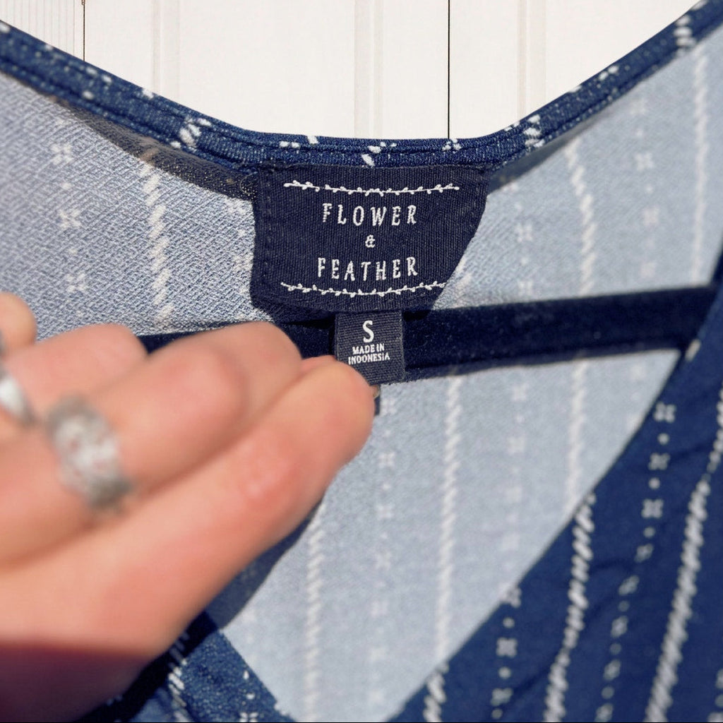 Close-up of a garment label on a blue and white patterned fabric with a hand holding it.