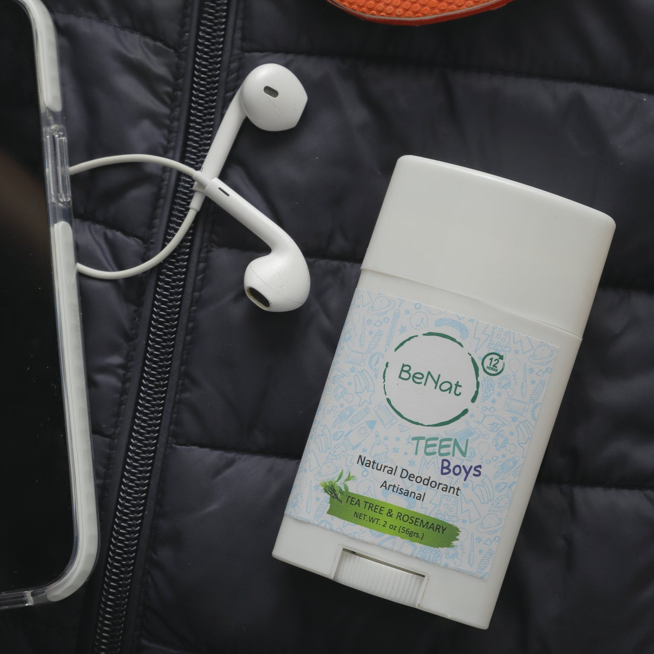 Deodorant stick for teens on a black jacket with earphones and a phone