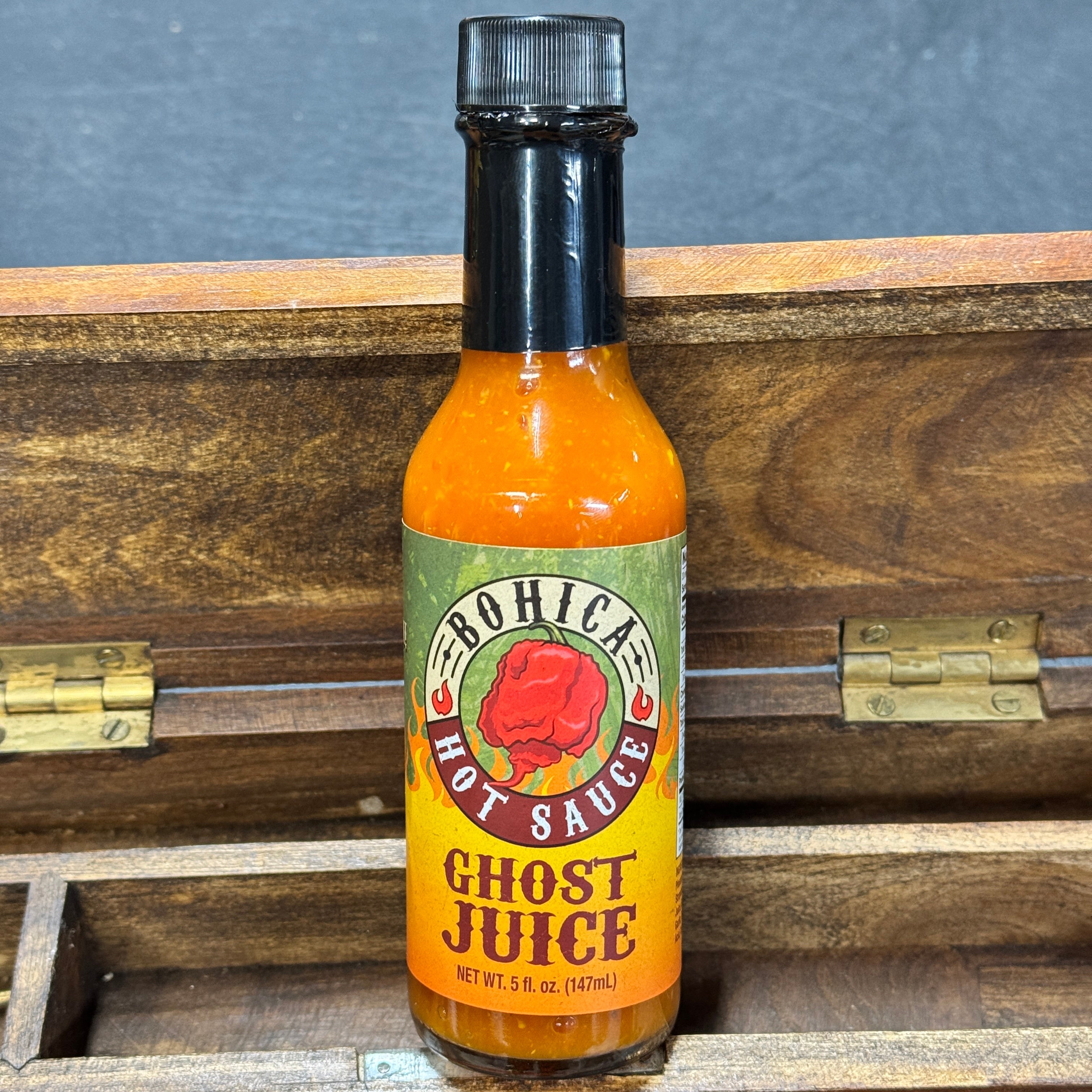 Bottle of Bohica Ghost Juice hot sauce on a wooden surface