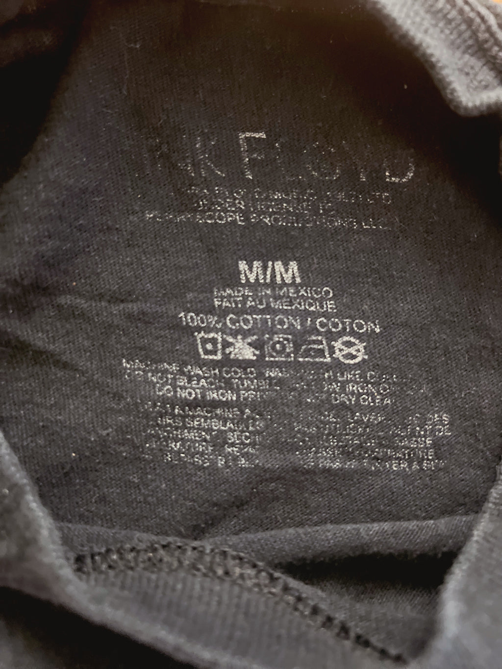 Close-up of the inside neck label of a dark gray or black cotton t-shirt, showing the brand name 'Nike Floyd' and care instructions.