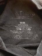 Close-up of the inside neck label of a dark gray or black cotton t-shirt, showing the brand name 'Nike Floyd' and care instructions.