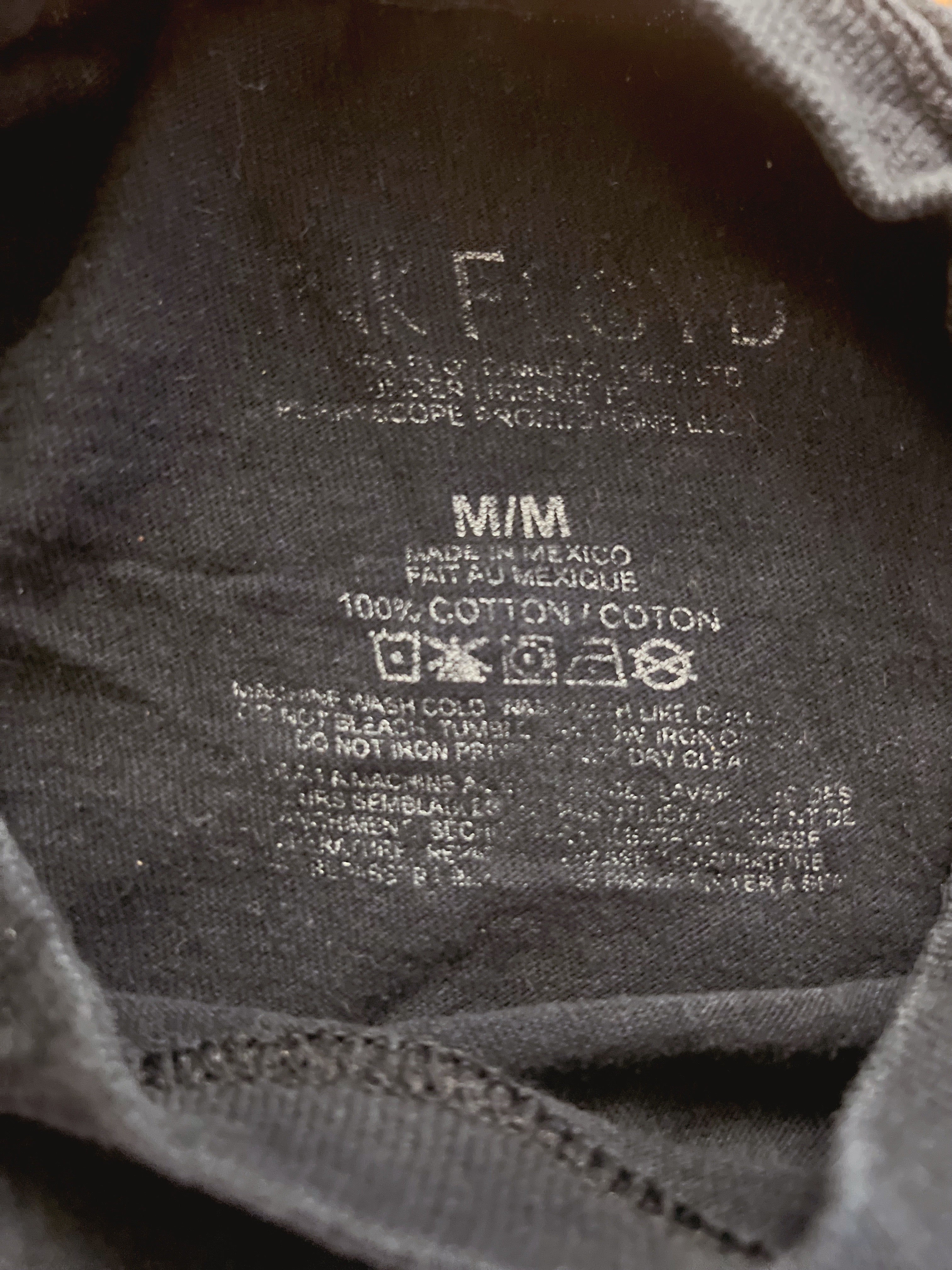 Close-up of the inside neck label of a dark gray or black cotton t-shirt, showing the brand name 'Nike Floyd' and care instructions.