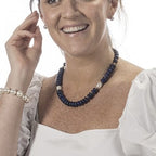 Woman wearing a white dress with a blue beaded necklace on a white background