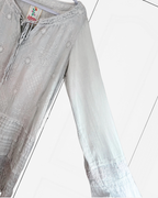Gray eyelet embroidered cupra rayon long-sleeve blouse with a tie-neck detail, shown hanging on a white hanger against a white paneled background