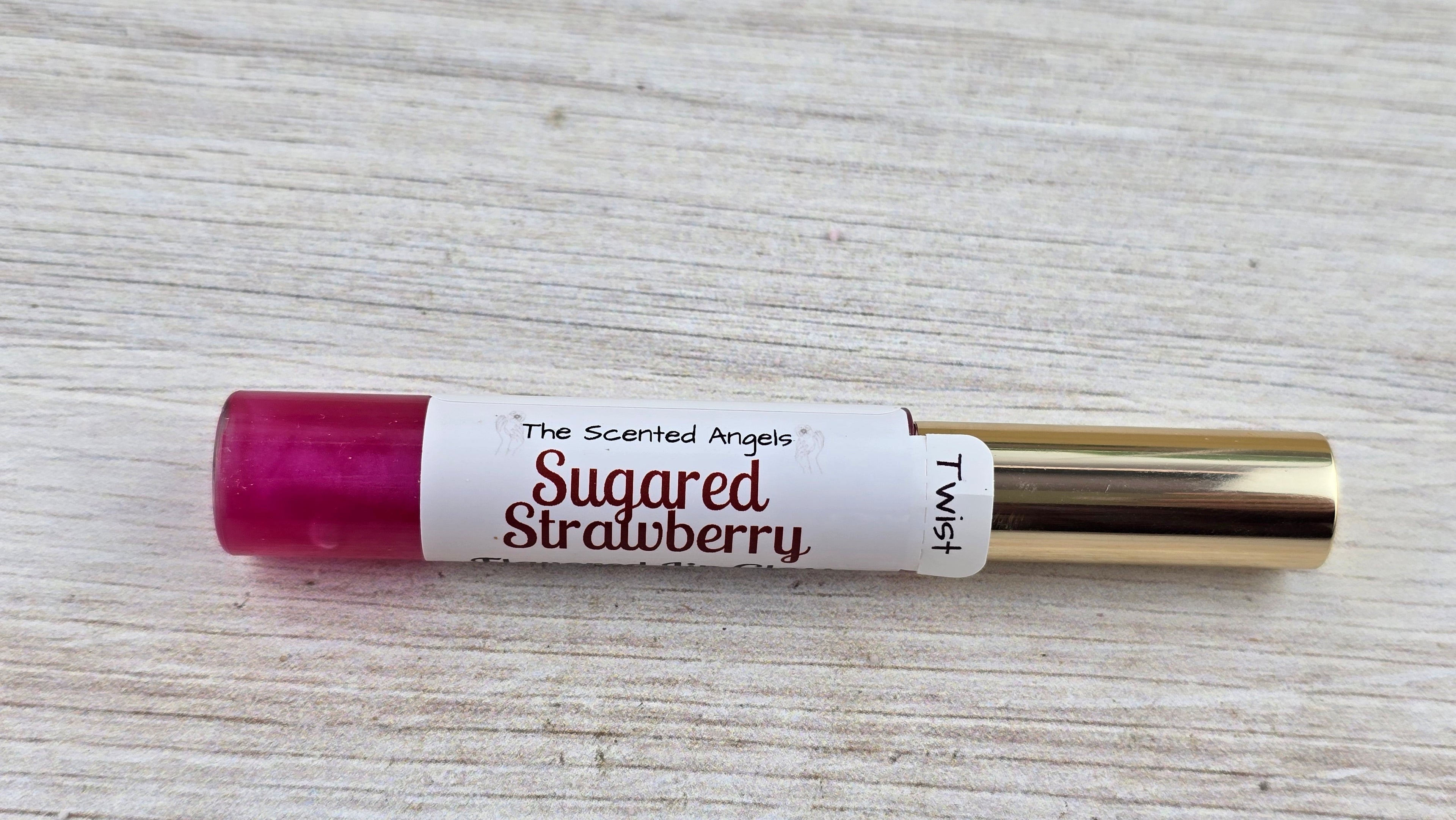Scented rollerball labeled 'Sugared Strawberry' by 'The Scented Angels' on a wooden surface.