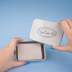 Person holding a metallic tin with 'UpCircle' branding against a blue background