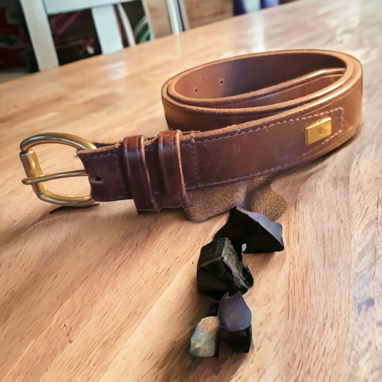Brown leather belt with gold buckle on a wooden surface