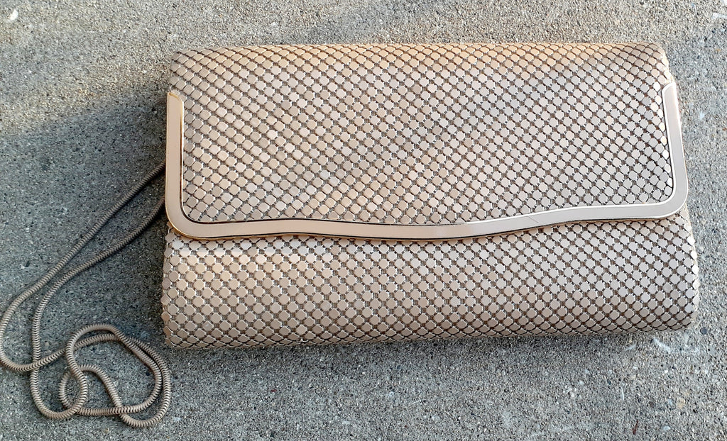 Beige textured clutch bag on a gray surface