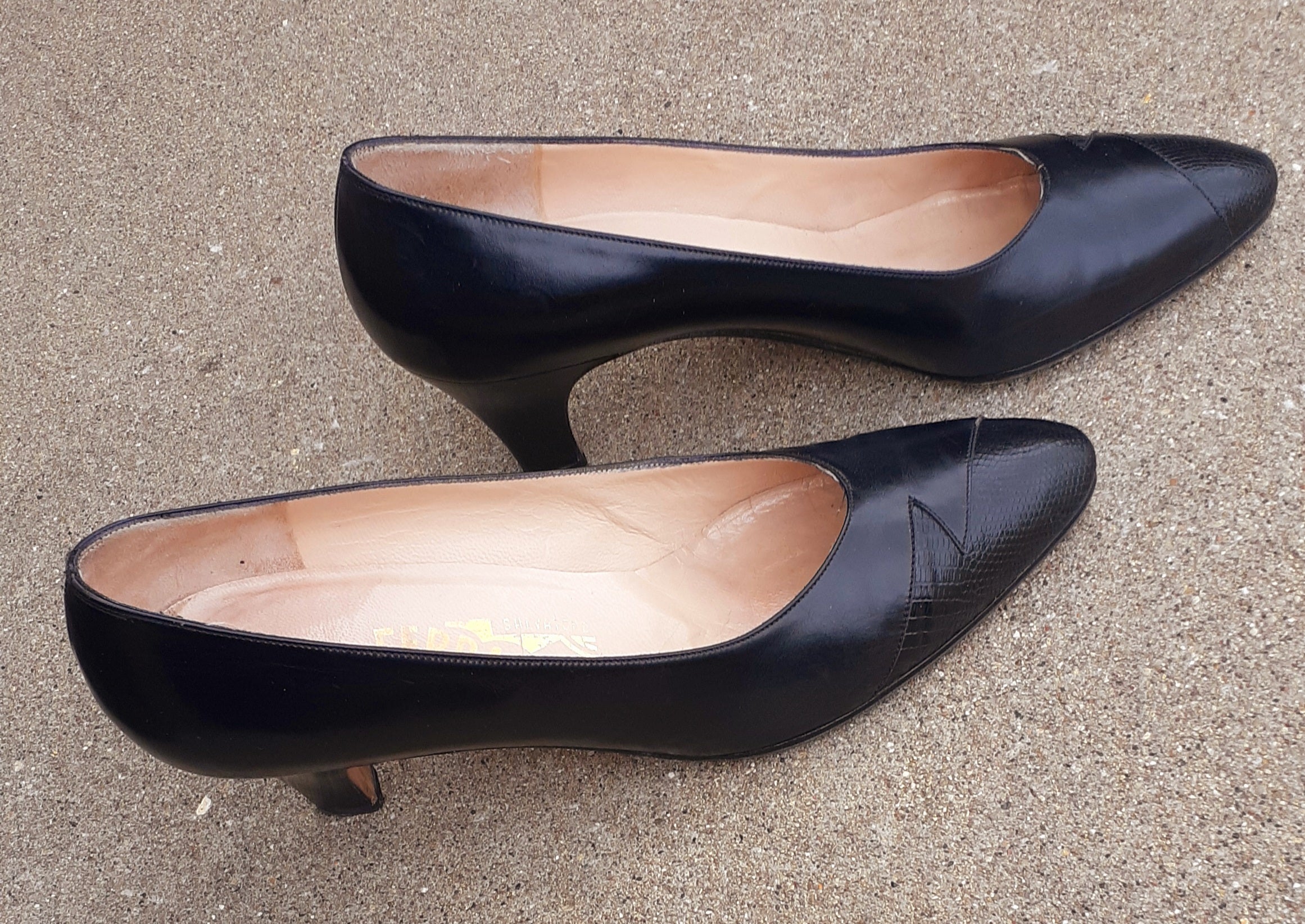 Pair of black high-heeled shoes on a gray surface
