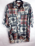 A short-sleeve button-up shirt with a mixed graphic print featuring plaid patterns, palm trees, and architectural elements in red, beige, gray, and black, hanging on a black hanger against a white background.