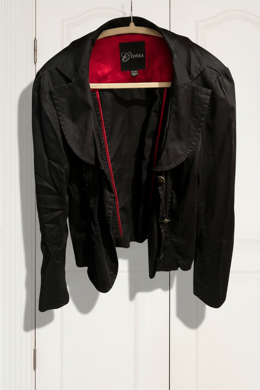 Black jacket with red zipper on a hanger against a white wall