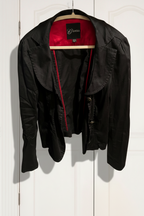 Black jacket with red zipper on a hanger against a white wall