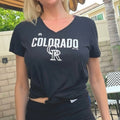 Person wearing a black 'Colorado' t-shirt with a logo outdoors.
