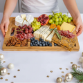Person holding a wooden charcuterie board with various foods on a festive background