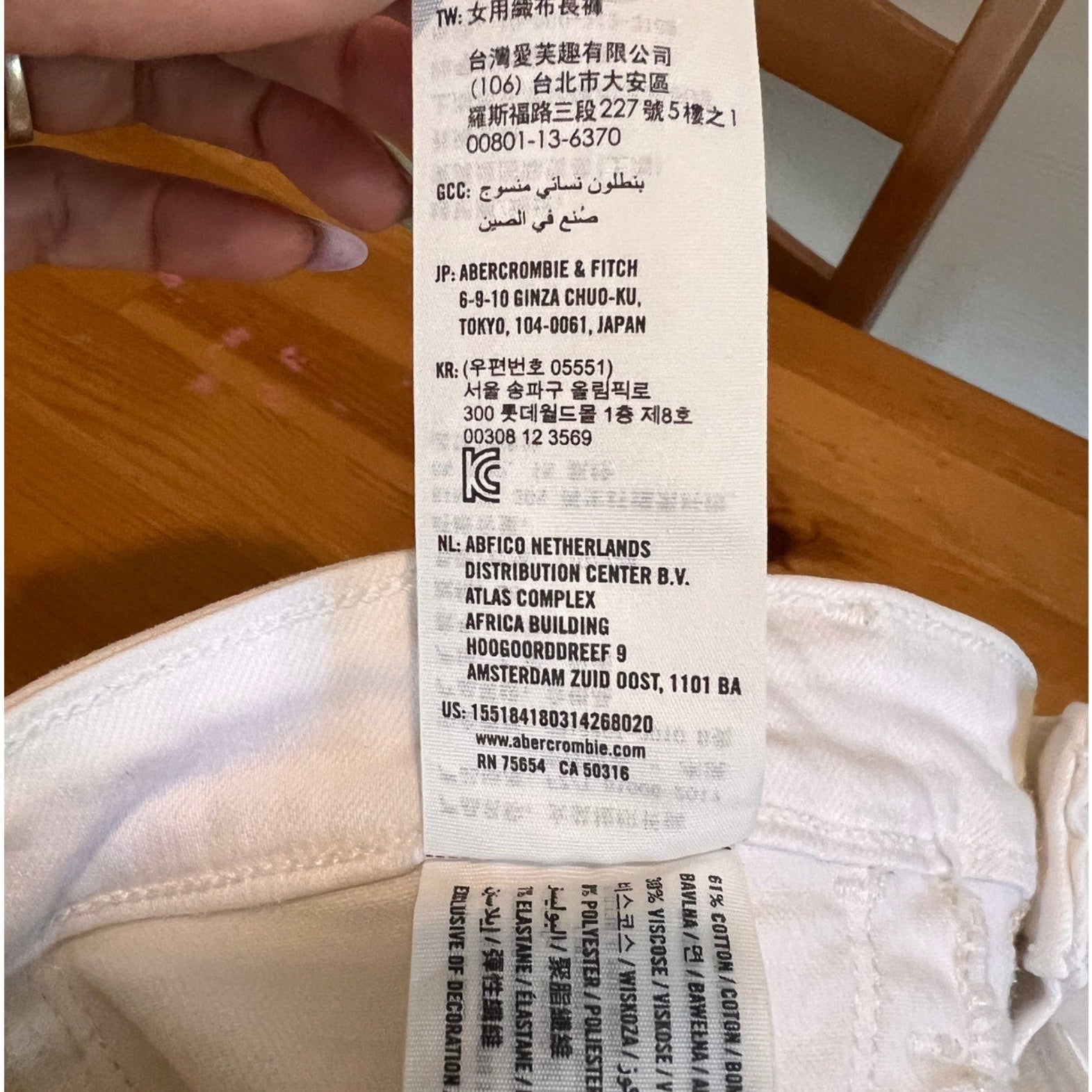 Close-up of a label on a white garment with text and a barcode.