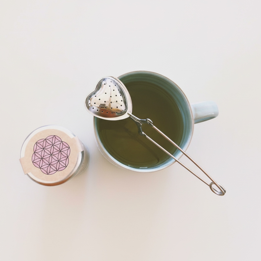 Tea cup with a metal tea infuser and a decorative container on a light background